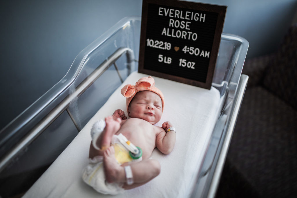 A newborn baby stretches out in its hospital bassinet for a fresh 48 newborn photography session.