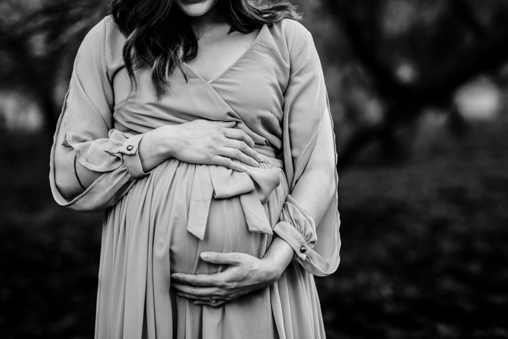 A pregnant mother hugs her belly during a maternity photography session in Arizona.